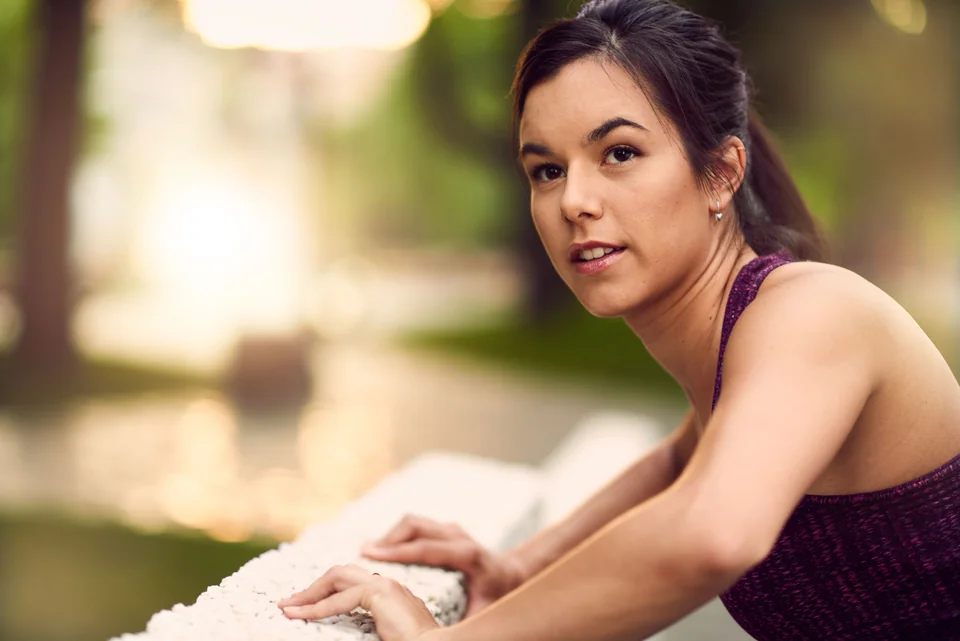 Portrait of active millenial woman jogging at dusk with an urban cityscape and sunset in the background