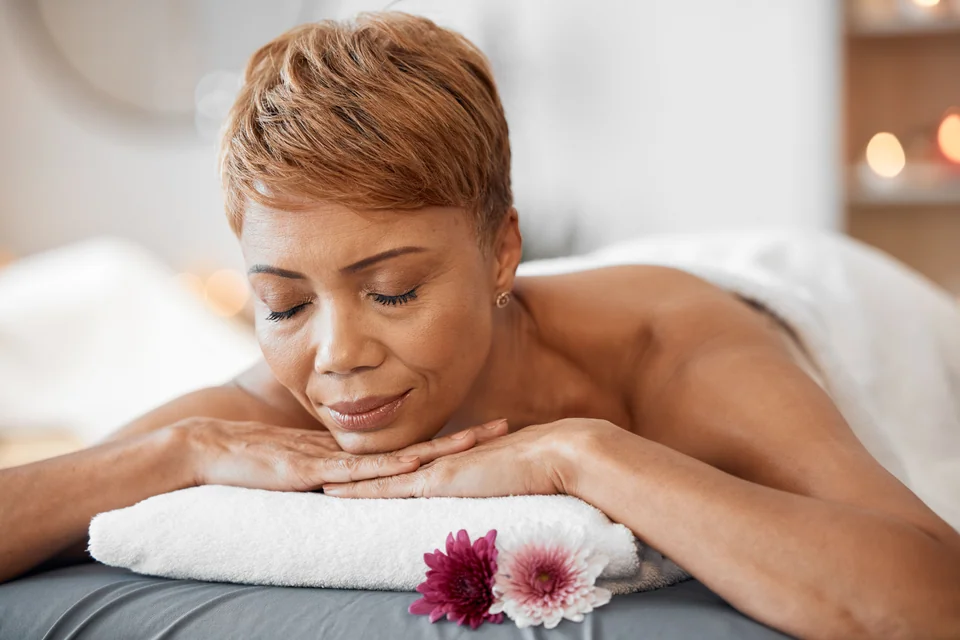 Wellness, massage and black woman at spa sleeping on cosmetology salon bed for relaxing back treatment. Relax, peace and calm client ready for professional beauty and luxury body care service.